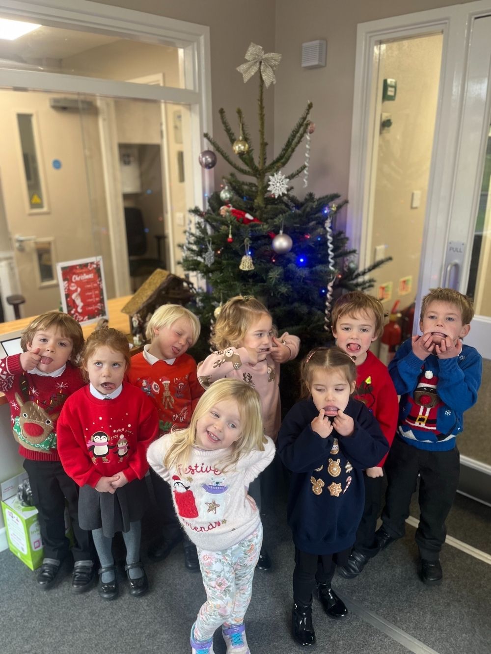 St Dominic Primary Pupils pulling faces by the christmas tree